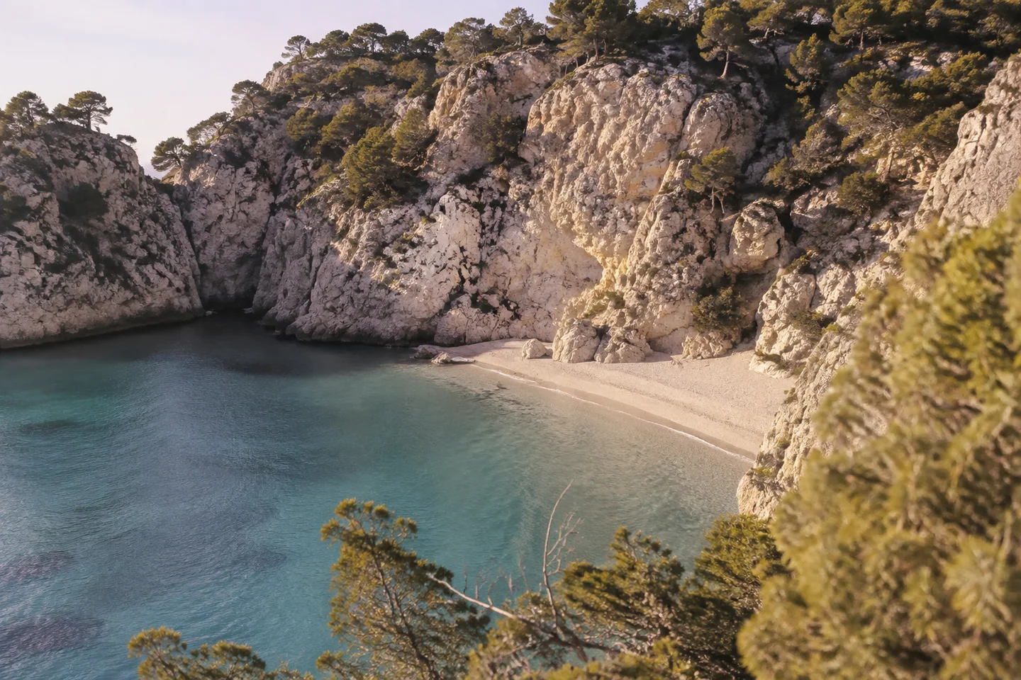 A secluded Mediterranean beach nestled between pale cliffs