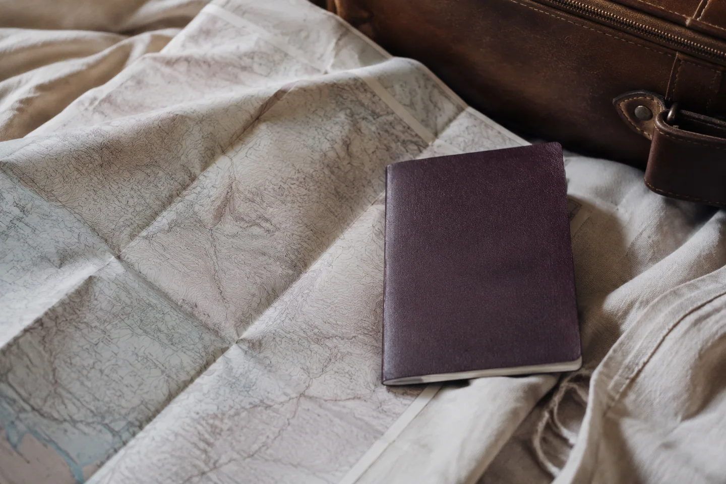 An open map and elegant travel essentials on natural linen